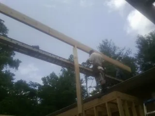 Carpenter setting a ridge beam over a new addition frame — Ice Dam Removal by Roofing Brothers in Sandy Creek
