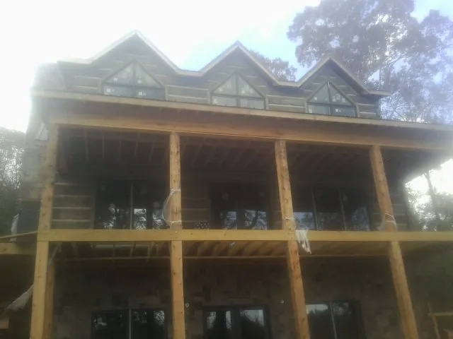 Dormers and porch framing on a large log home under construction — Roof Coating work by our crew in Sandy Creek