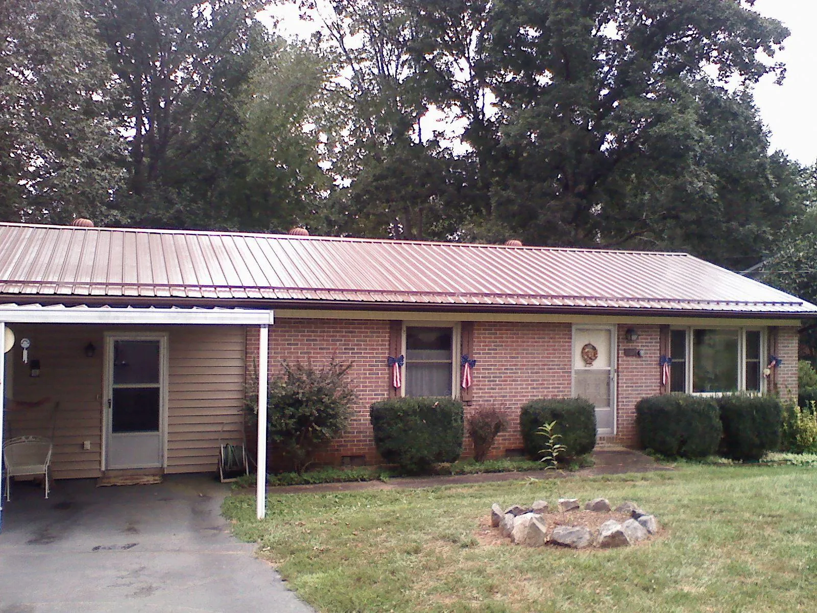 Bronze metal roof and carport on a brick ranch home — Roof Repair work by our crew in Sandy Creek