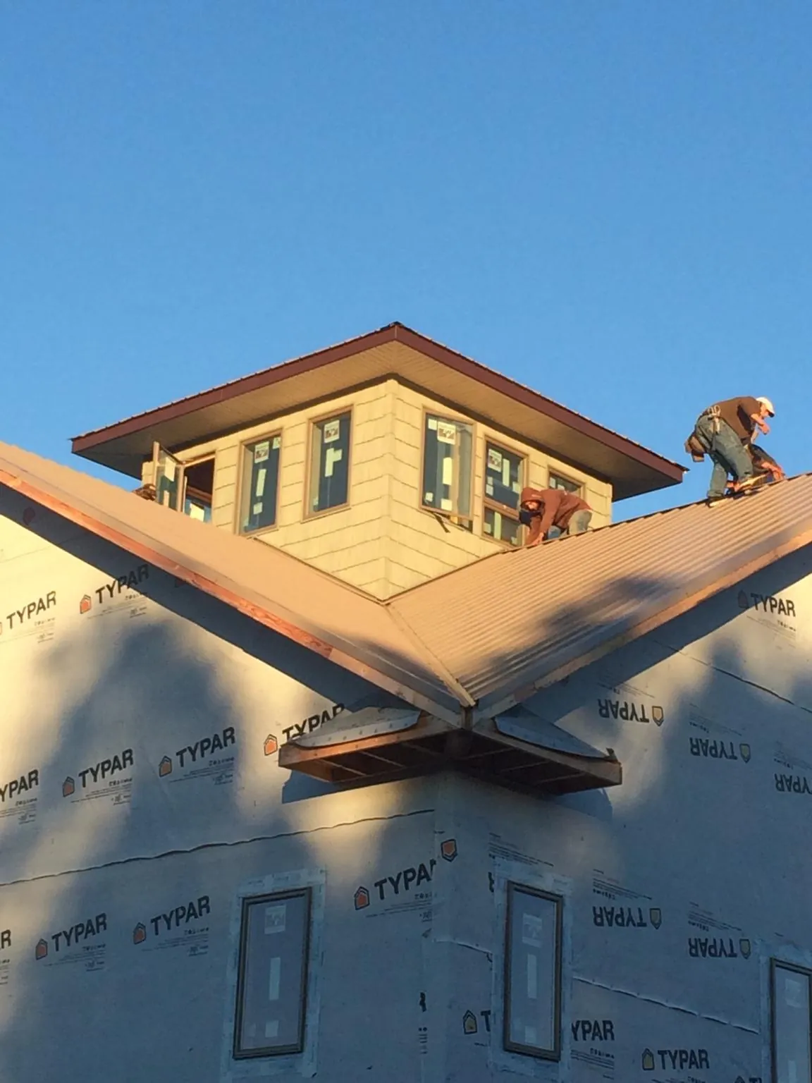 Roofers working around a rooftop cupola on a new metal roof at sunset — Roof Waterproofing in Sandy Creek by Roofing Brothers